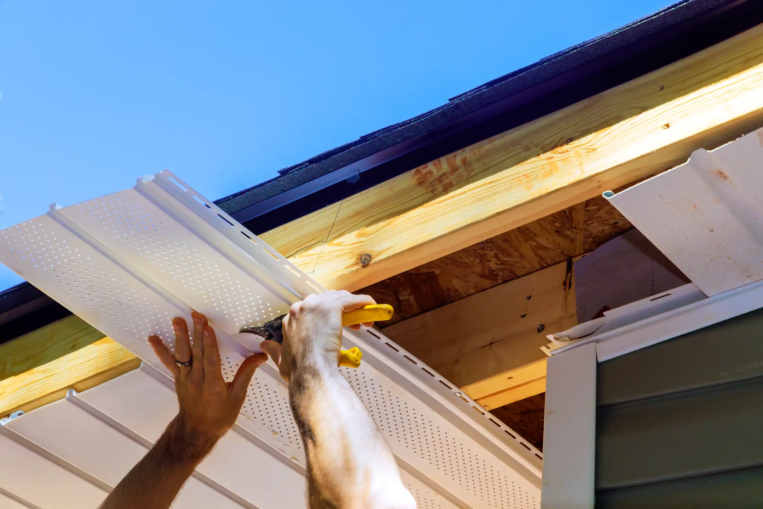 Vinyl soffit plastic panels into facade ceiling of new house by an employee