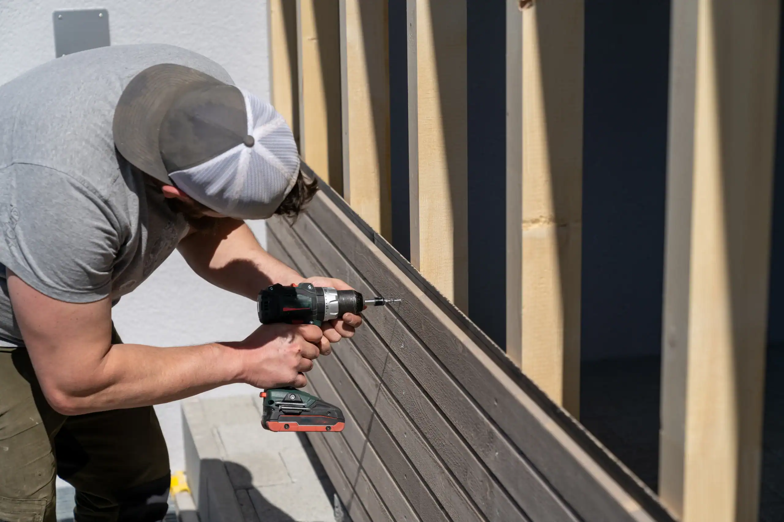 A tough construction worker applies wooden siding to a home