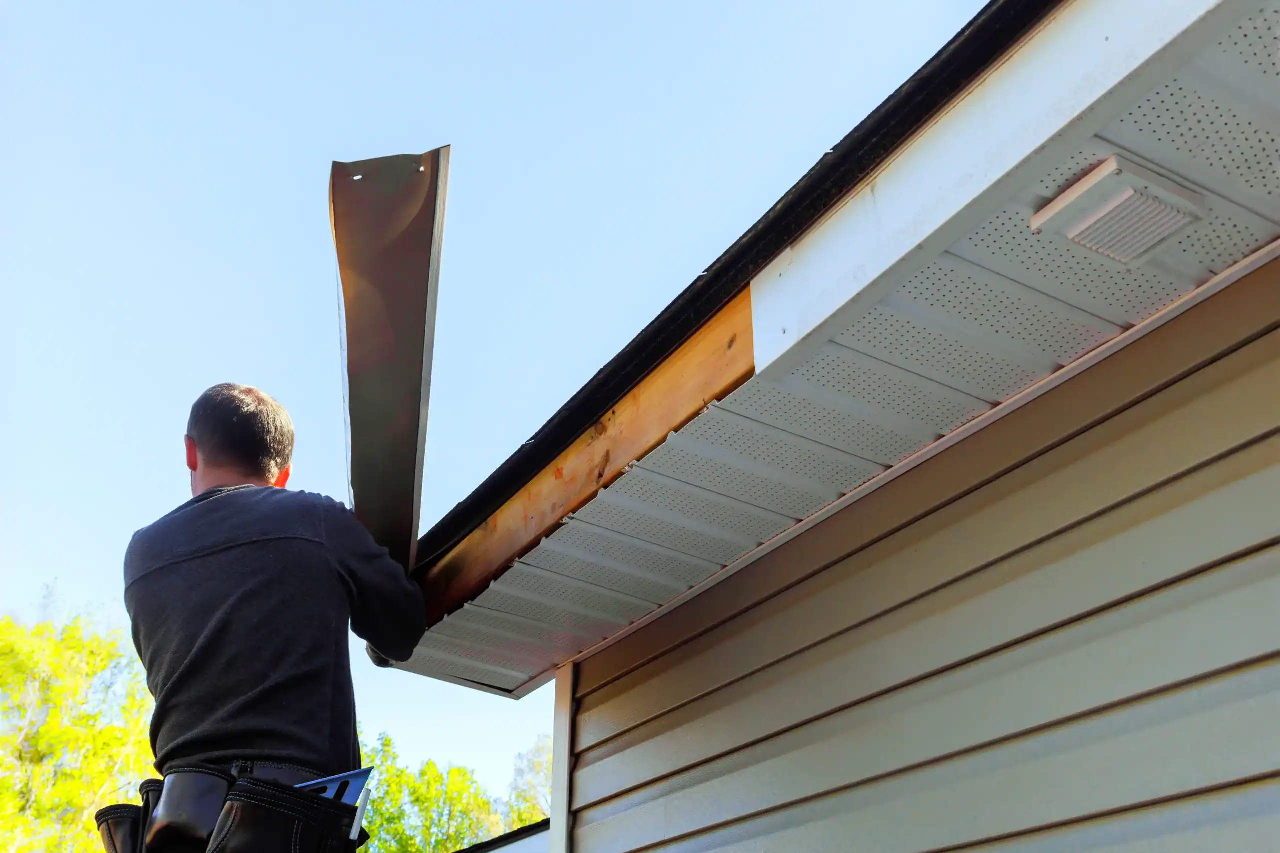 Installing fascia plastic panels on facade ceiling of a new home by an employee