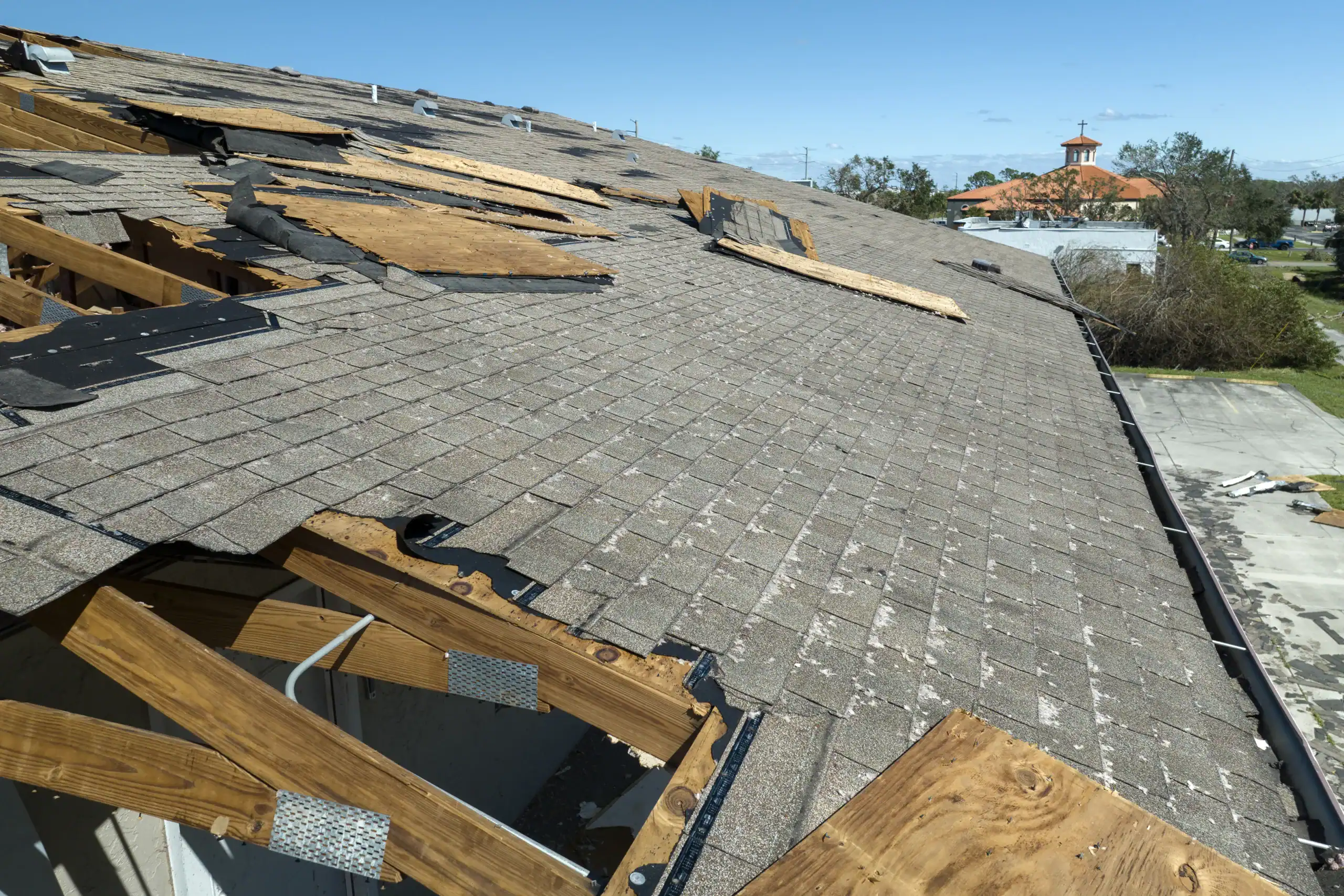 Consequences of natural disaster. Damaged house roof with missing shingles after storm.