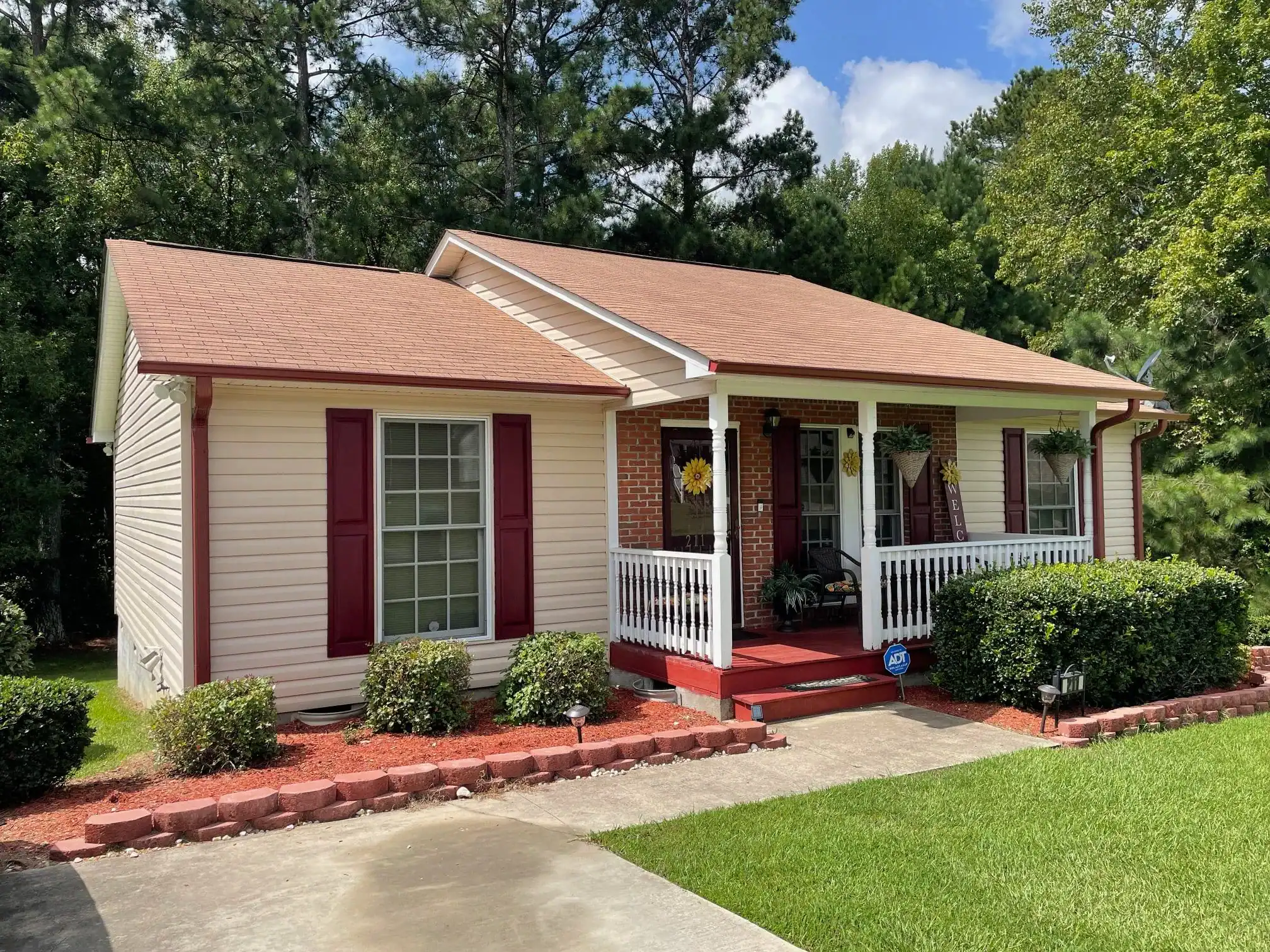 Beautiful suburban house with a welcoming front porch and well-maintained landscaping. Perfect for f.