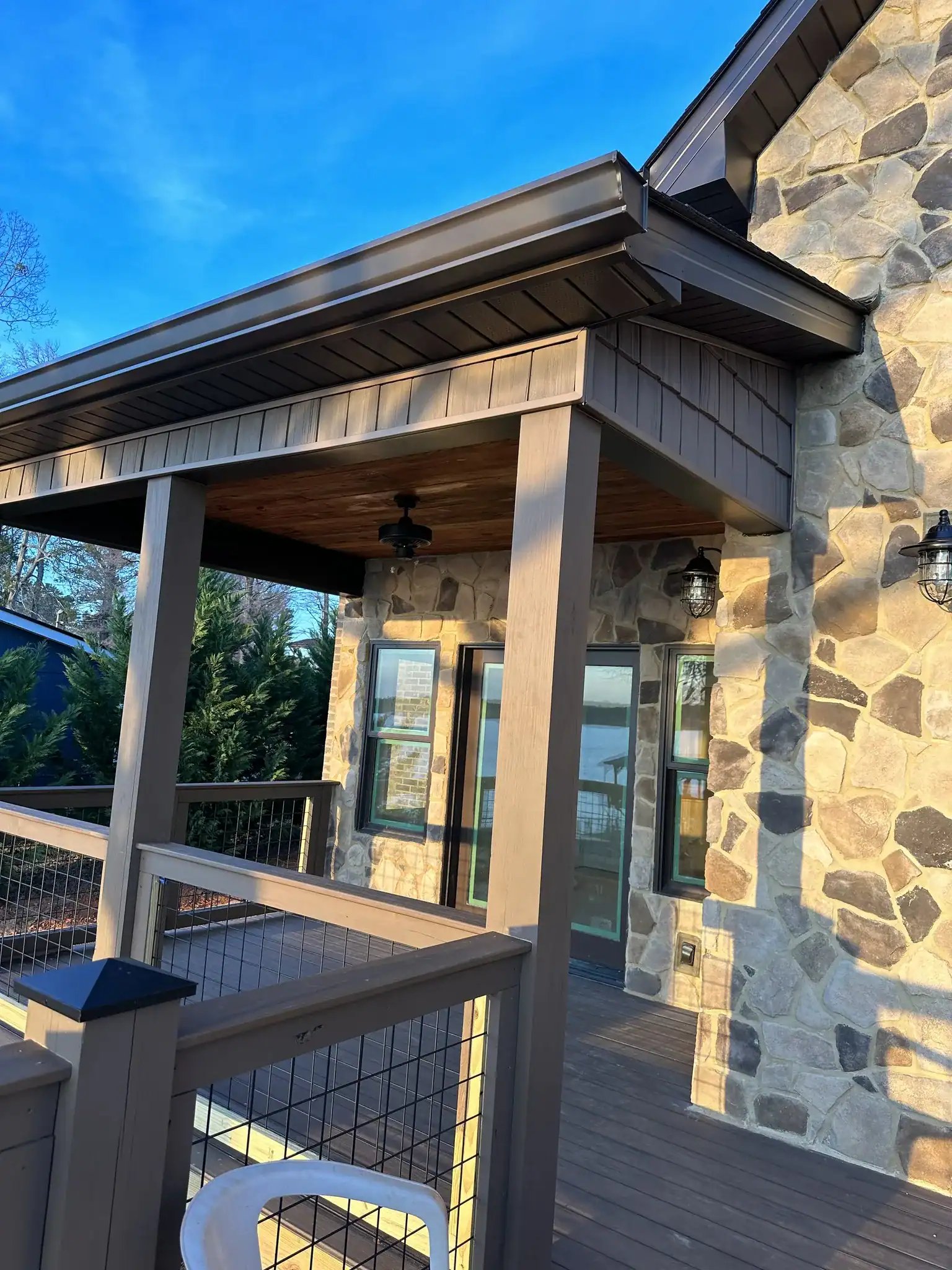 Exterior porch with stone walls and wooden accents, featuring a covered seating area and outdoor lig.