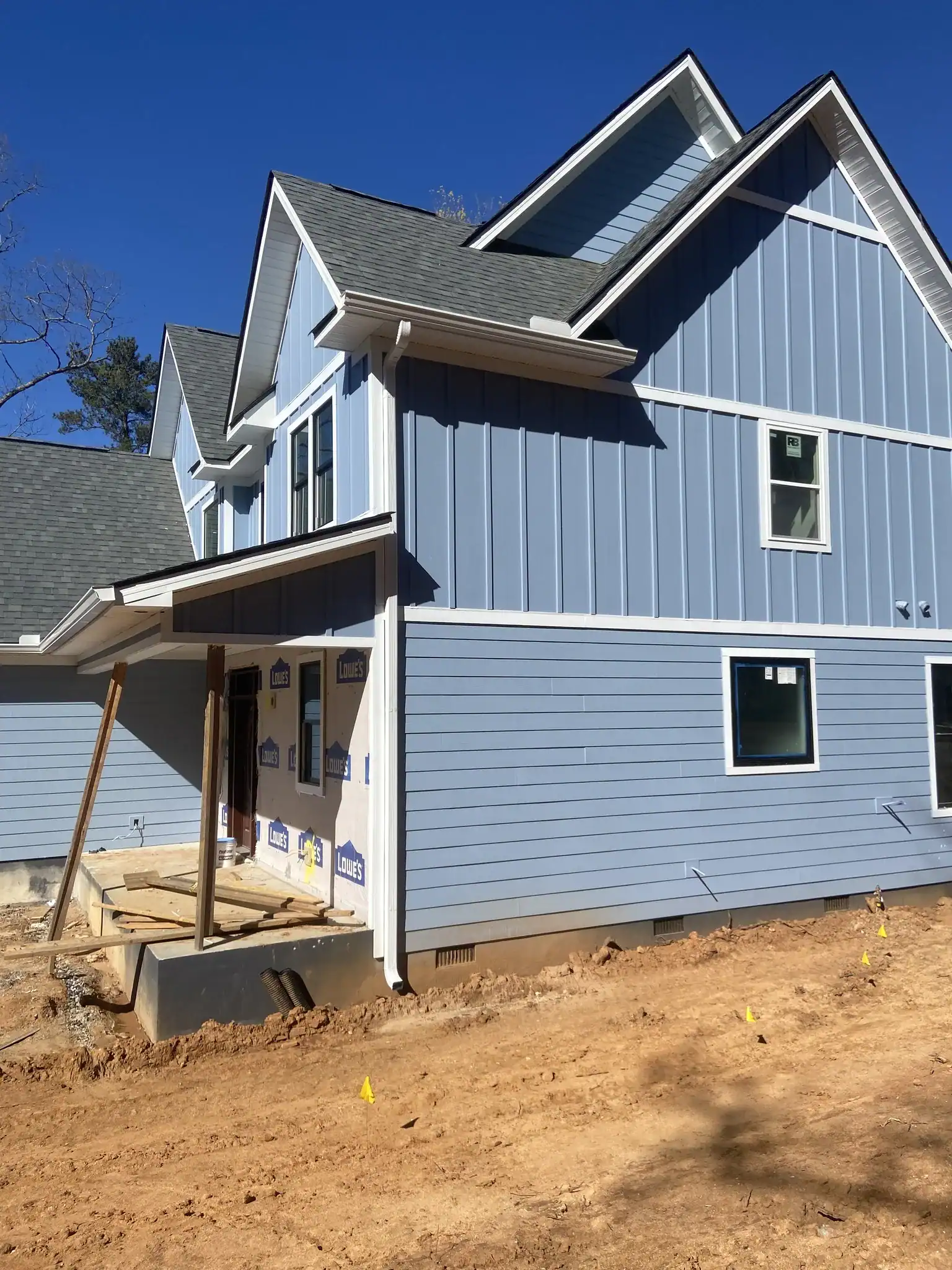 New blue house exterior under construction with siding and roof details.