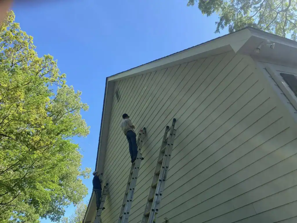 Exterior house painting with professional workers on ladders.