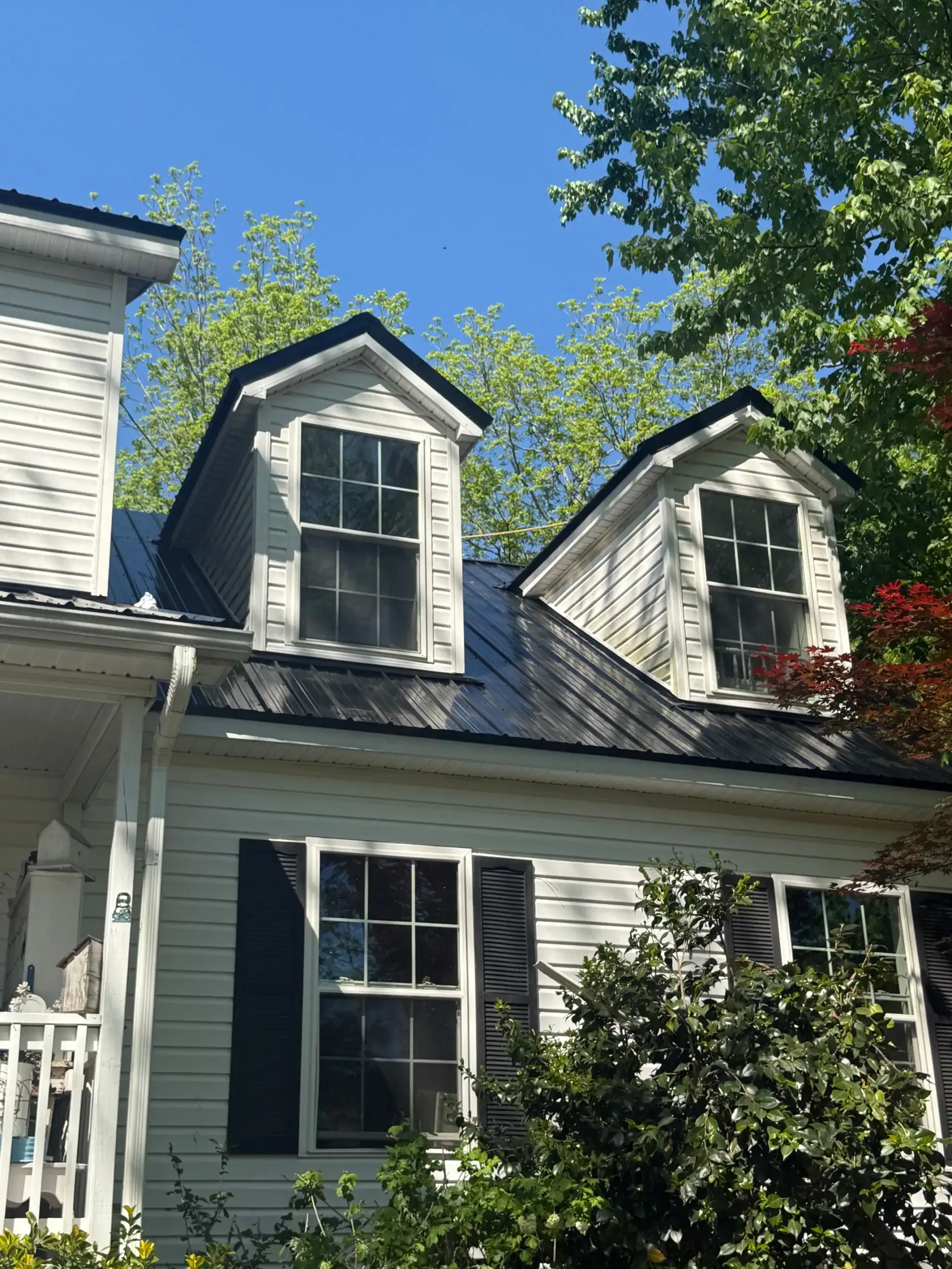 Exterior home with two dormer windows and white siding.